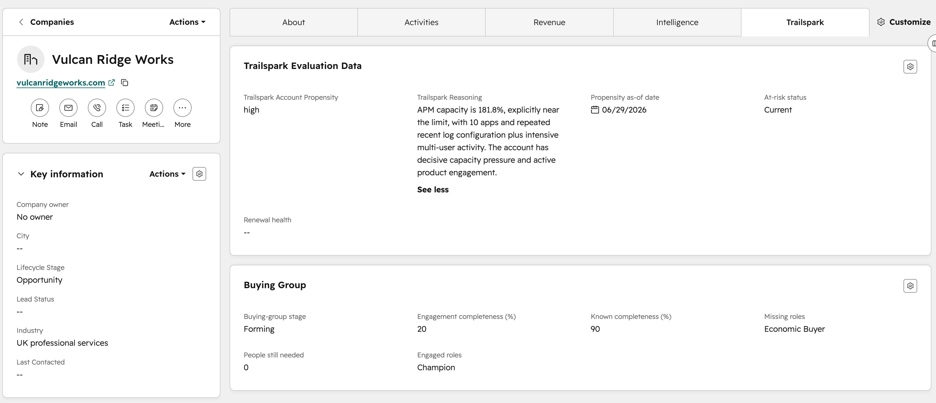 A HubSpot company record for Vulcan Ridge Works, a UK professional services company, with a custom Trailspark tab selected alongside the About, Activities, Revenue, and Intelligence tabs. A Trailspark Evaluation Data card shows account propensity high, an at-risk status of Current, and a written reason stating that APM capacity is 181.8 percent and near the limit, with 10 apps, repeated recent log configuration, and intensive multi-user activity indicating decisive capacity pressure and active product engagement. A Buying Group card below shows stage Forming, engagement completeness 20 percent, known completeness 90 percent, engaged role Champion, and missing role Economic Buyer.